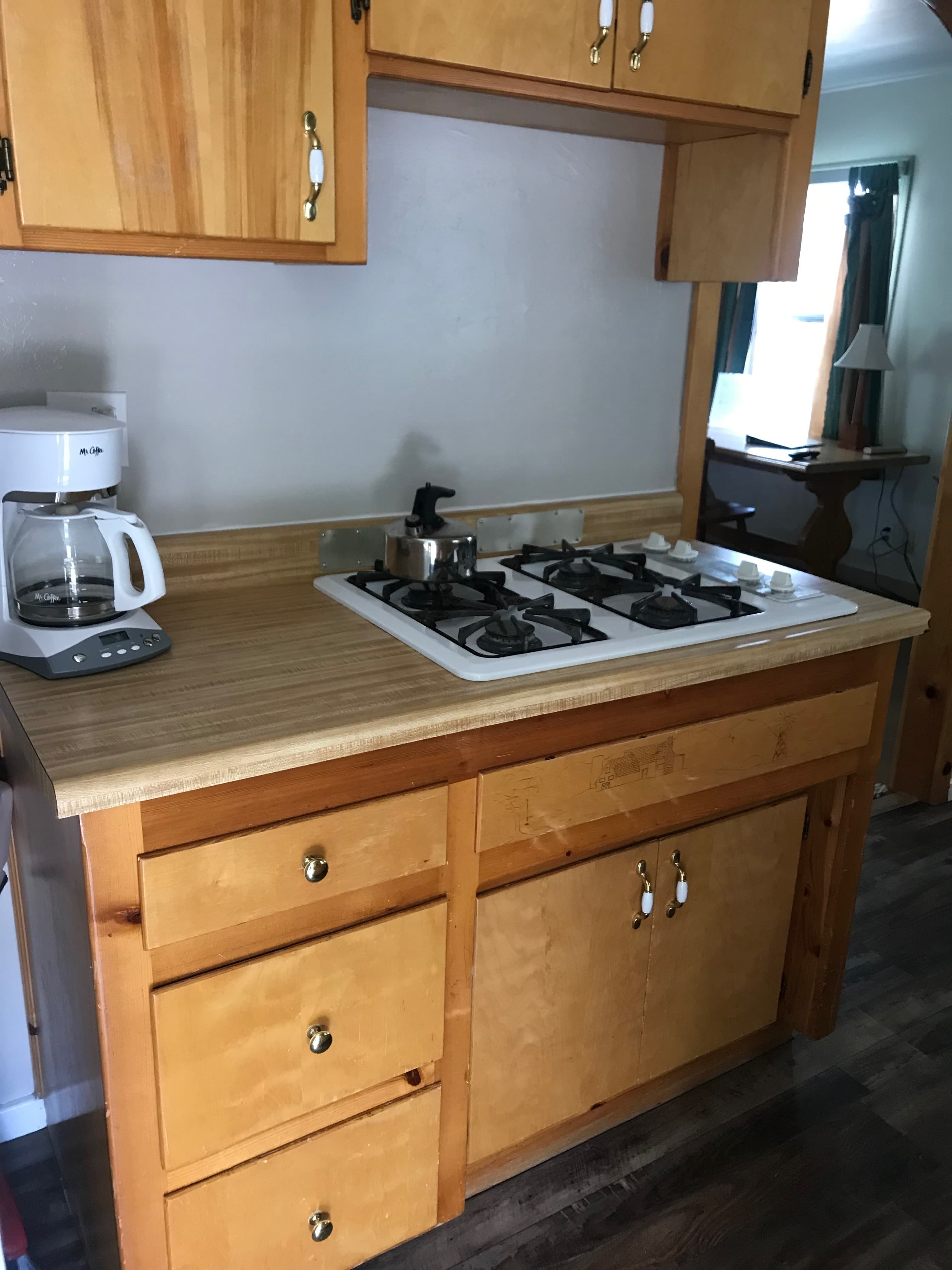 A wooden kitchen countertop featuring a gas stove and a coffee maker.