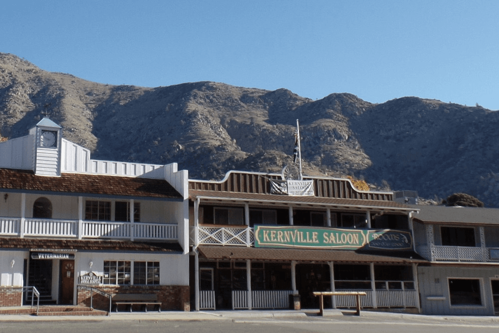 The Kernville Saloon sits at the foot of rugged mountains under a clear blue sky.