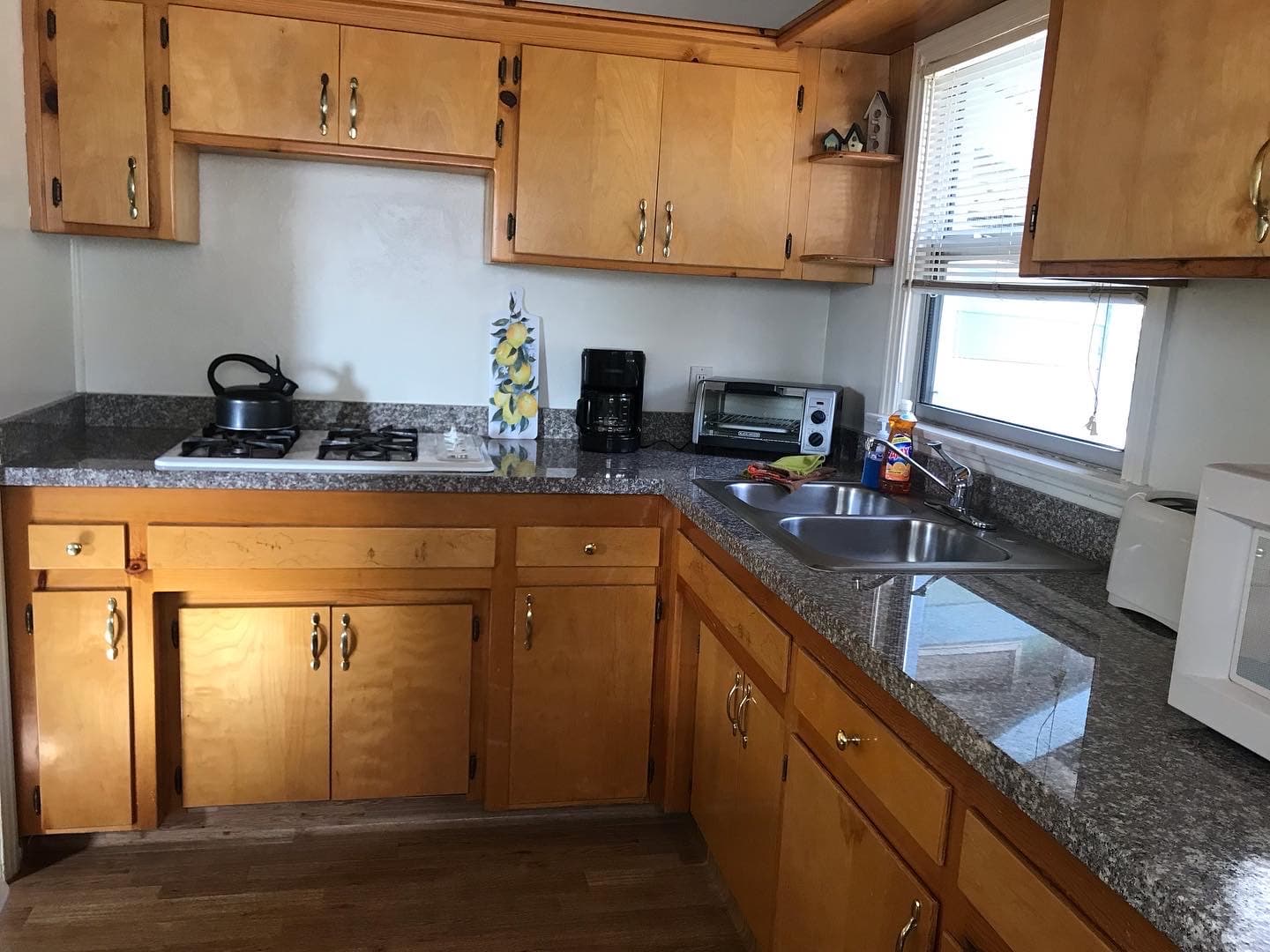 Bright kitchen with wooden cabinets, granite countertops, and various appliances.
