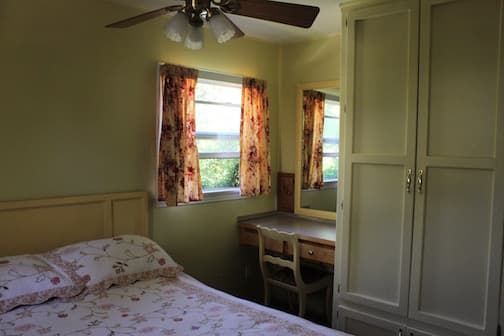 Cozy bedroom with a floral bedspread, a wooden desk, and yellow walls.