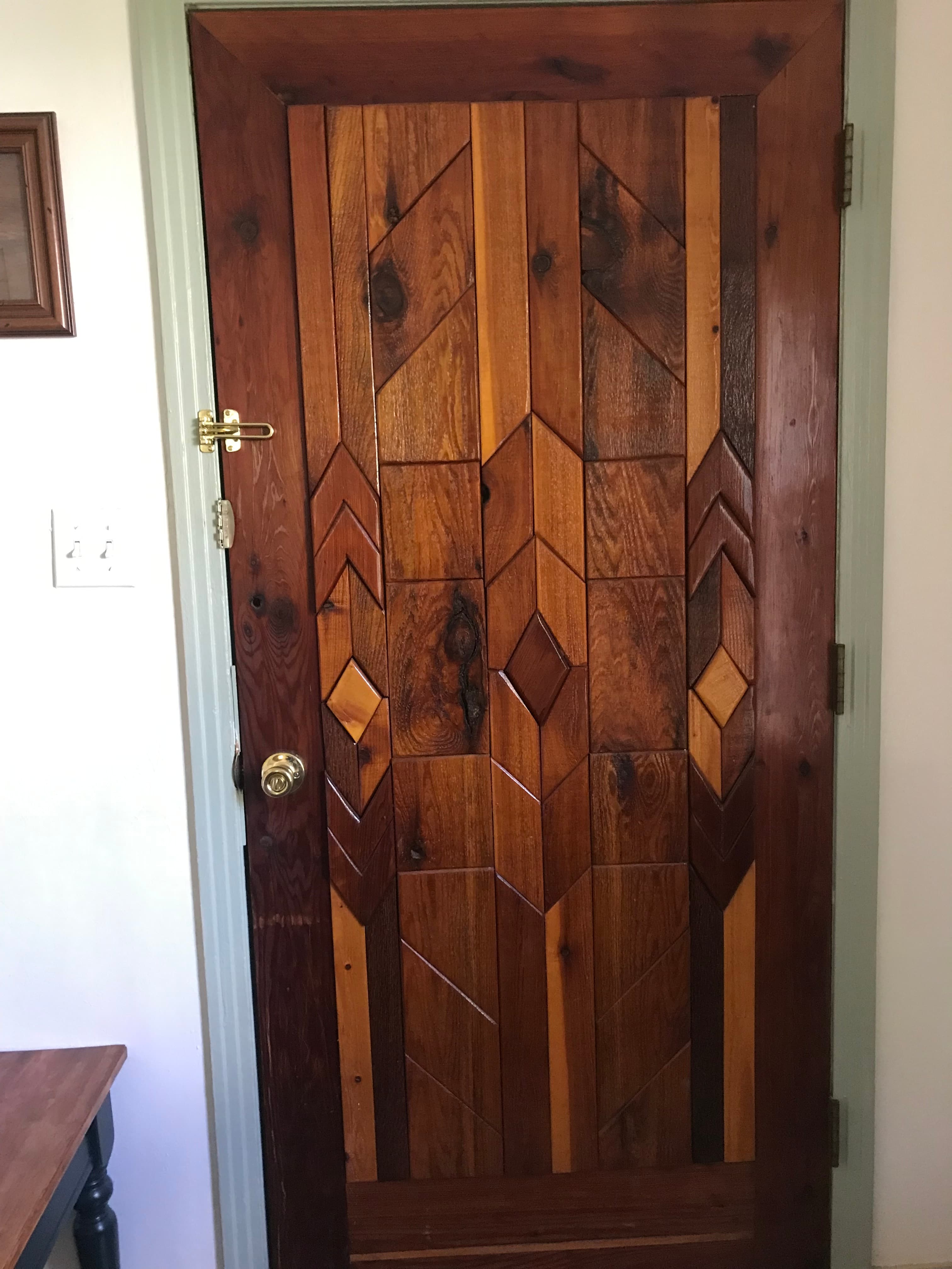 A wooden door with intricate geometric patterns and a brass handle.