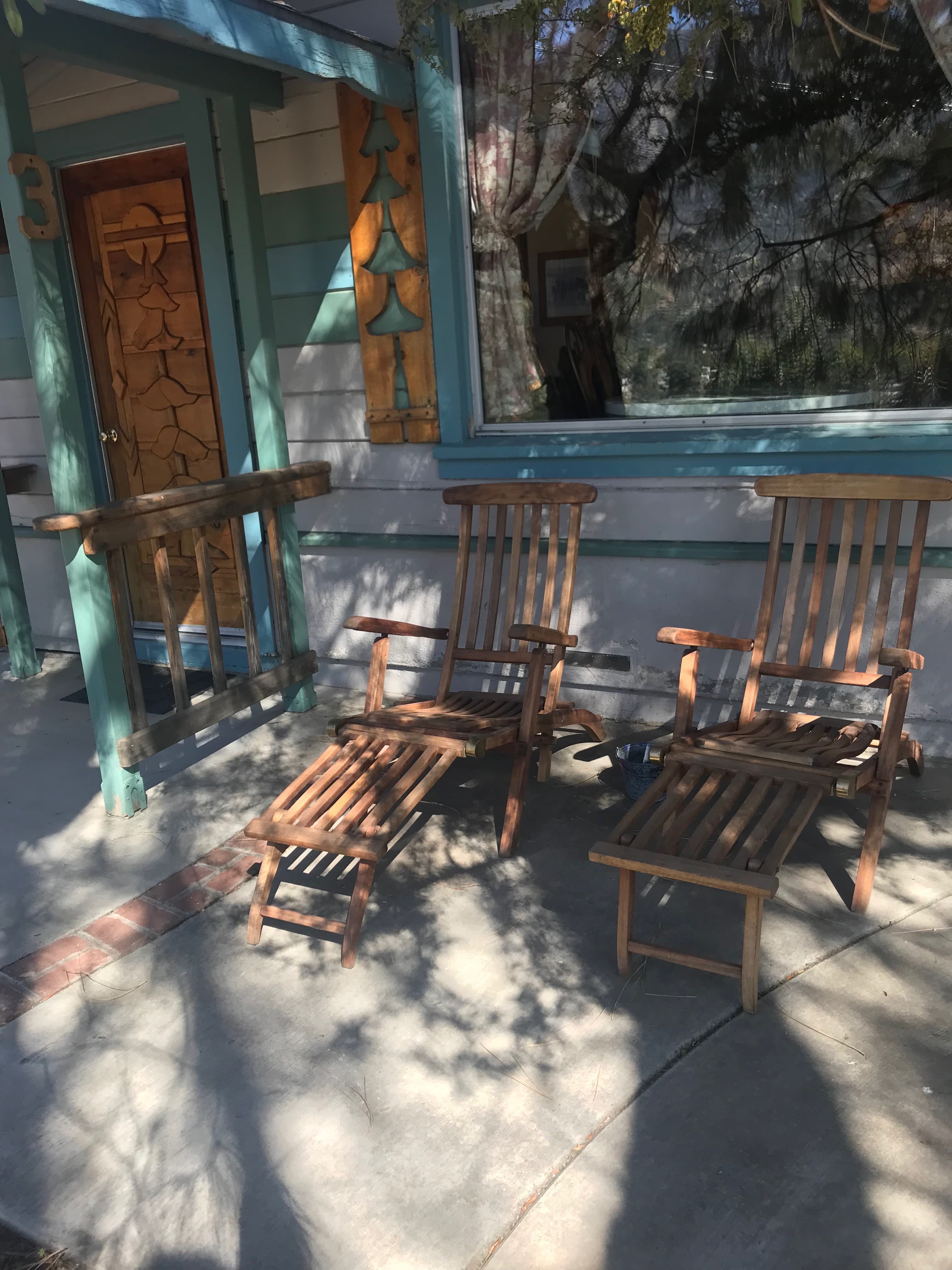 Sunlit porch featuring two wooden lounge chairs and a door with decorative paneling.