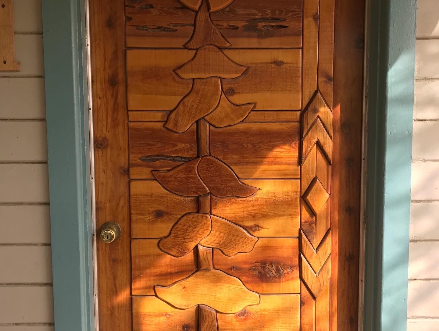 A wooden door featuring intricate carvings of leaves and geometric patterns.